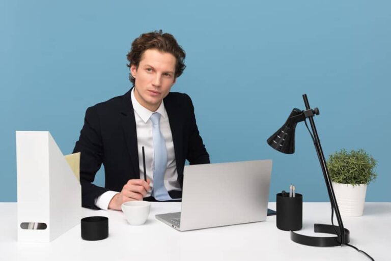 Un homme en costume assis à un bureau avec un ordinateur portable.